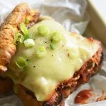 Keto BBQ Pulled Pork Sandwich on parchment paper with scallions and pickles