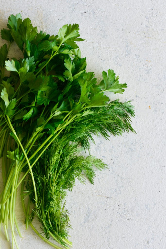 dill and parsley on a white surface image of dill and parsley on a white surface